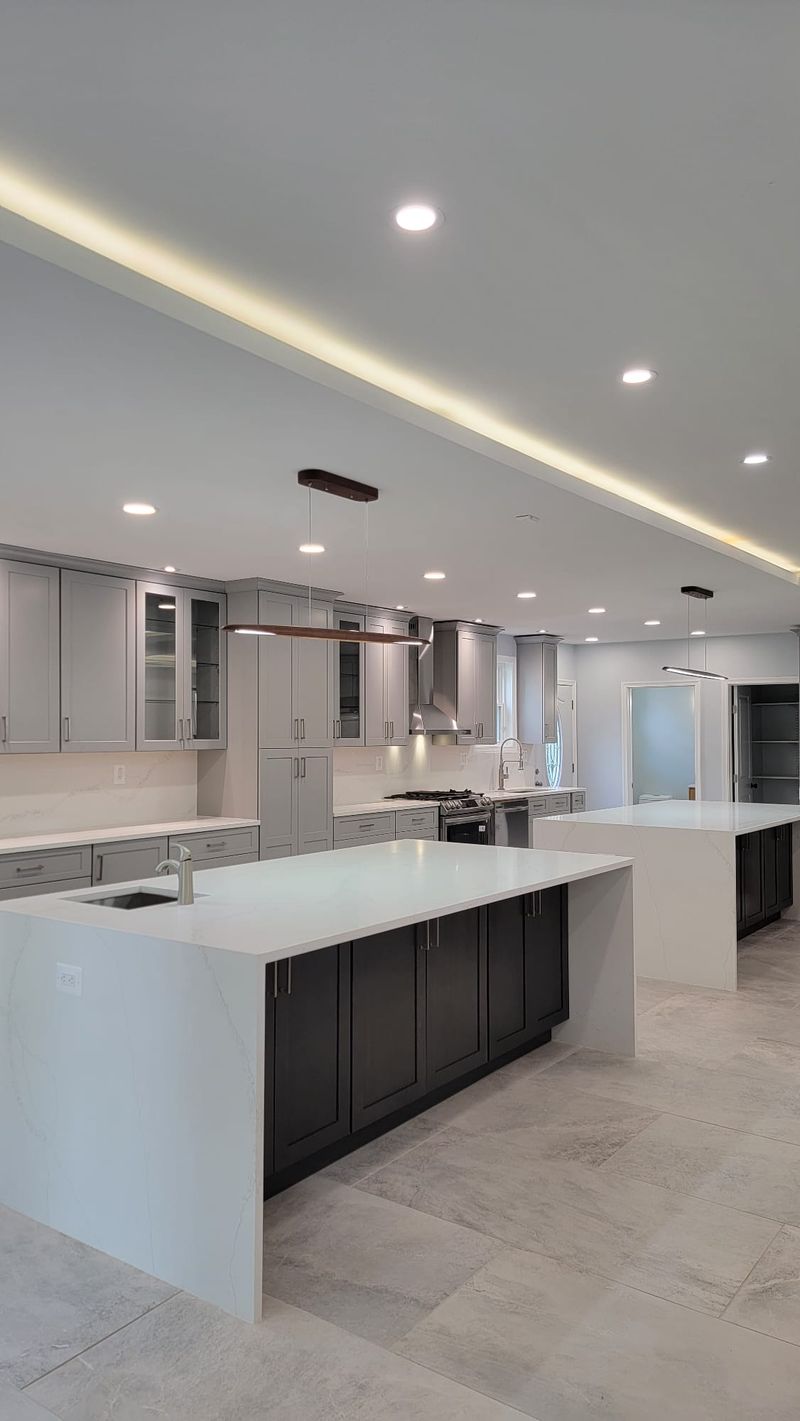 Wide view of double-island kitchen connecting to the living space