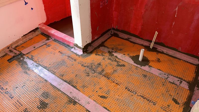 Orange waterproofing membrane covers the bathroom floor and shower area.