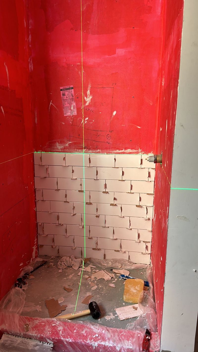 White subway tile is installed against red waterproofed shower walls.