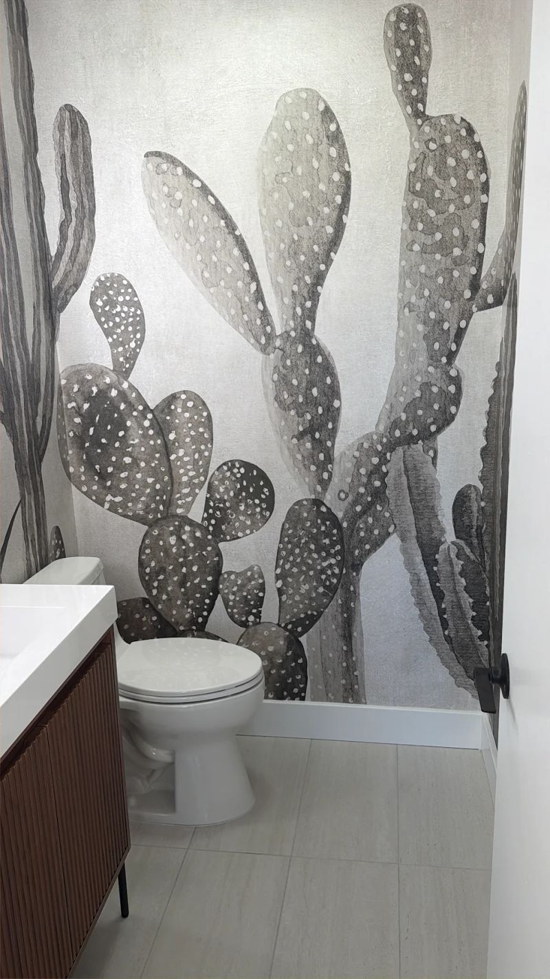 Finished cactus mural powder room with a fluted walnut vanity and matte black fixtures.