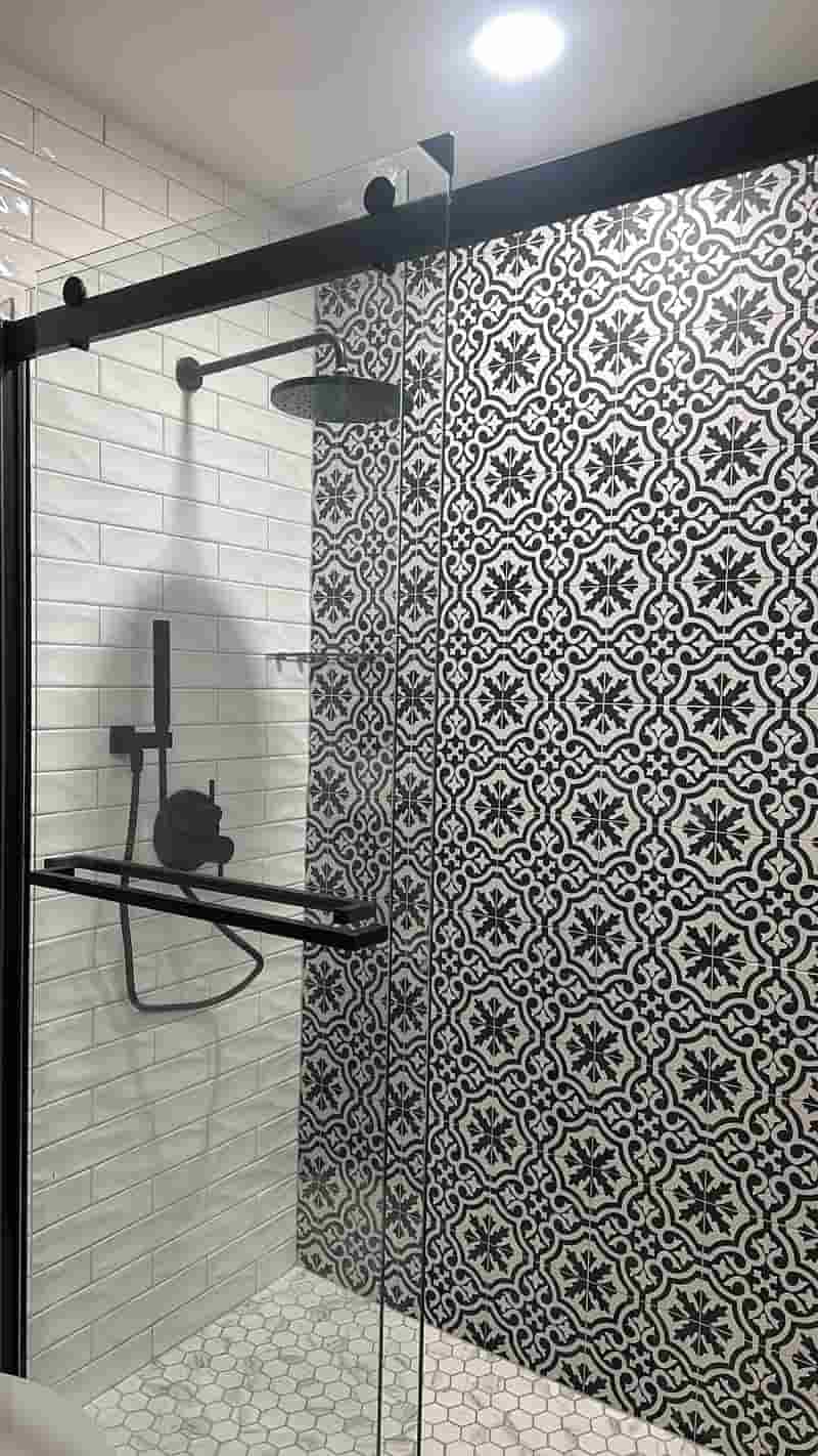Glass shower with black and white patterned accent tile