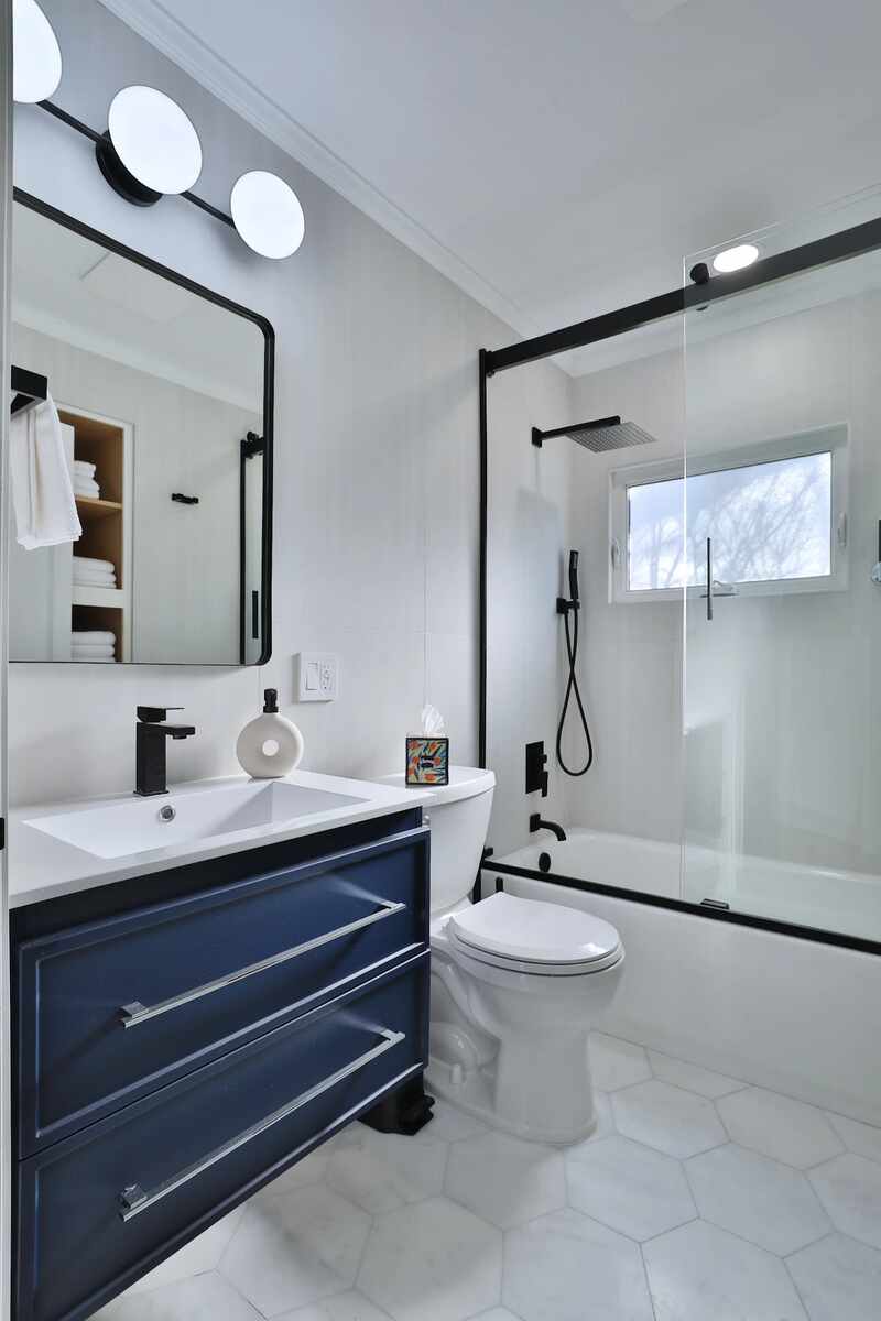 Blue bathroom vanity with white tile and matte black fixtures