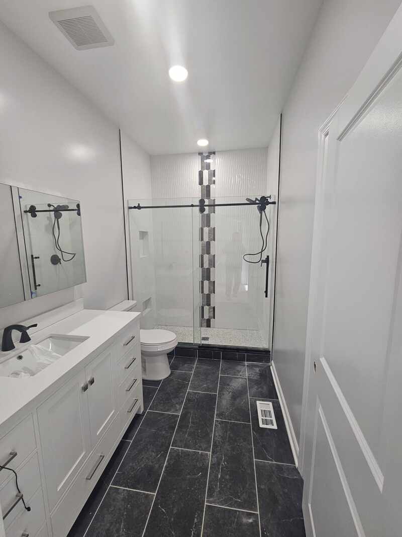 Bright white bathroom with a long vanity and dark floor tile
