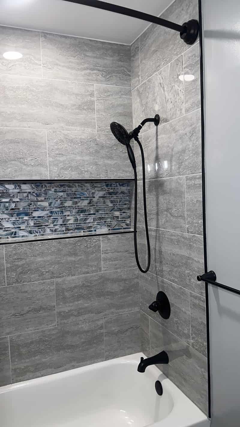 Gray tiled tub surround with a horizontal glass accent