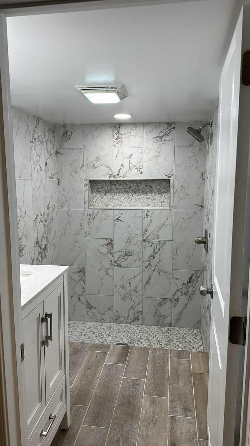 Marble look walk in shower with a hex mosaic niche