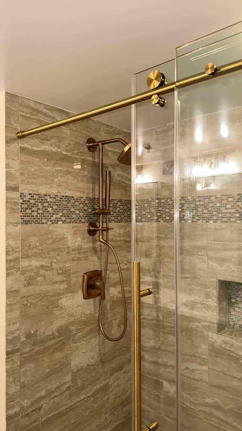 Gray tiled shower with warm metal fixtures